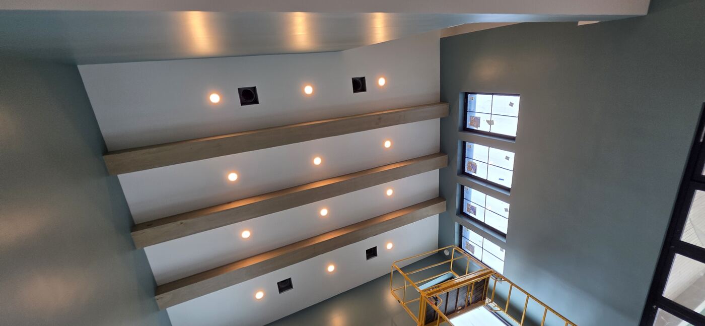 Recessed lighting installed across a vaulted residential ceiling with exposed beams.
