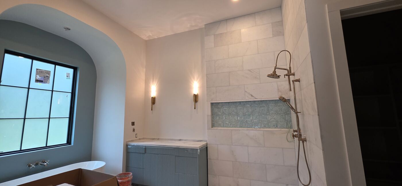 Pair of warm brass wall sconces installed beside a tiled residential shower.