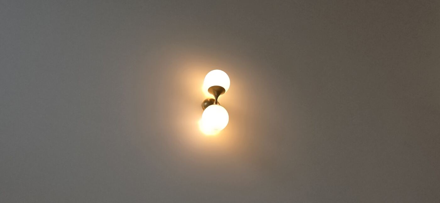 Warm two-globe wall sconce illuminated on a finished interior wall.