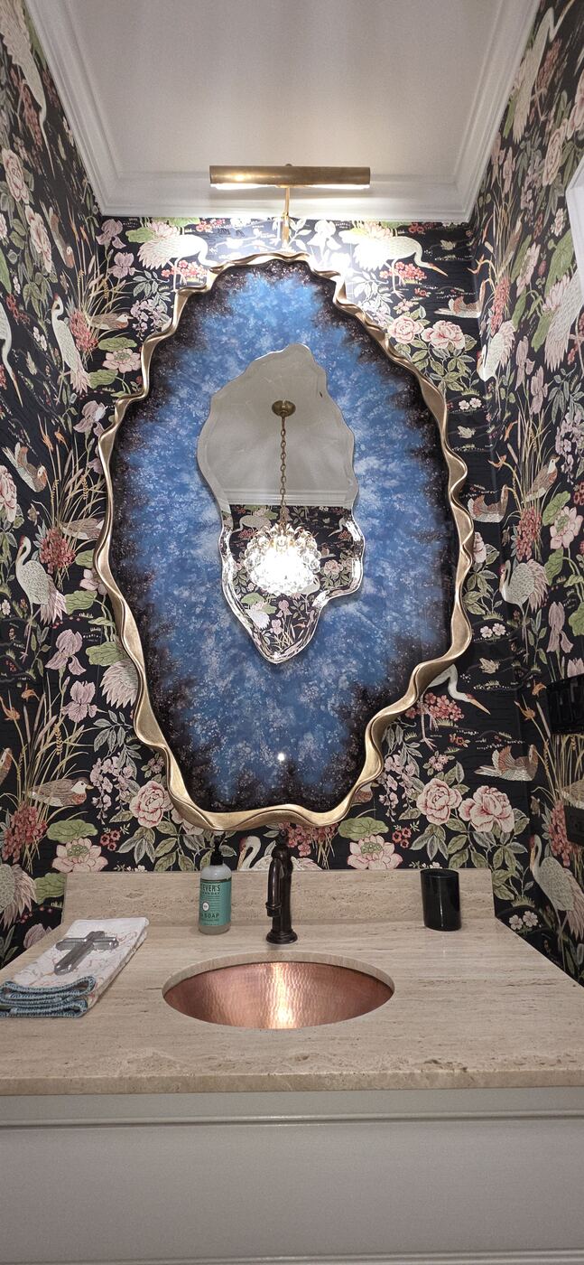 Finished powder room with illuminated statement mirror, vanity light and chandelier.